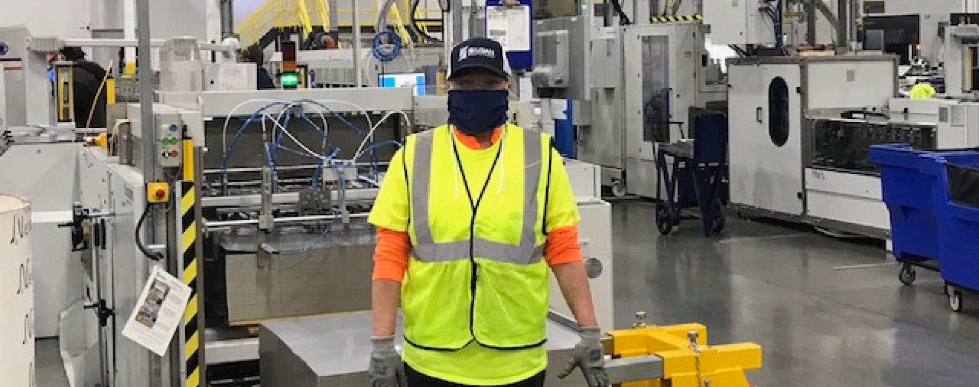 工人站在设备前，戴着高能见度装备